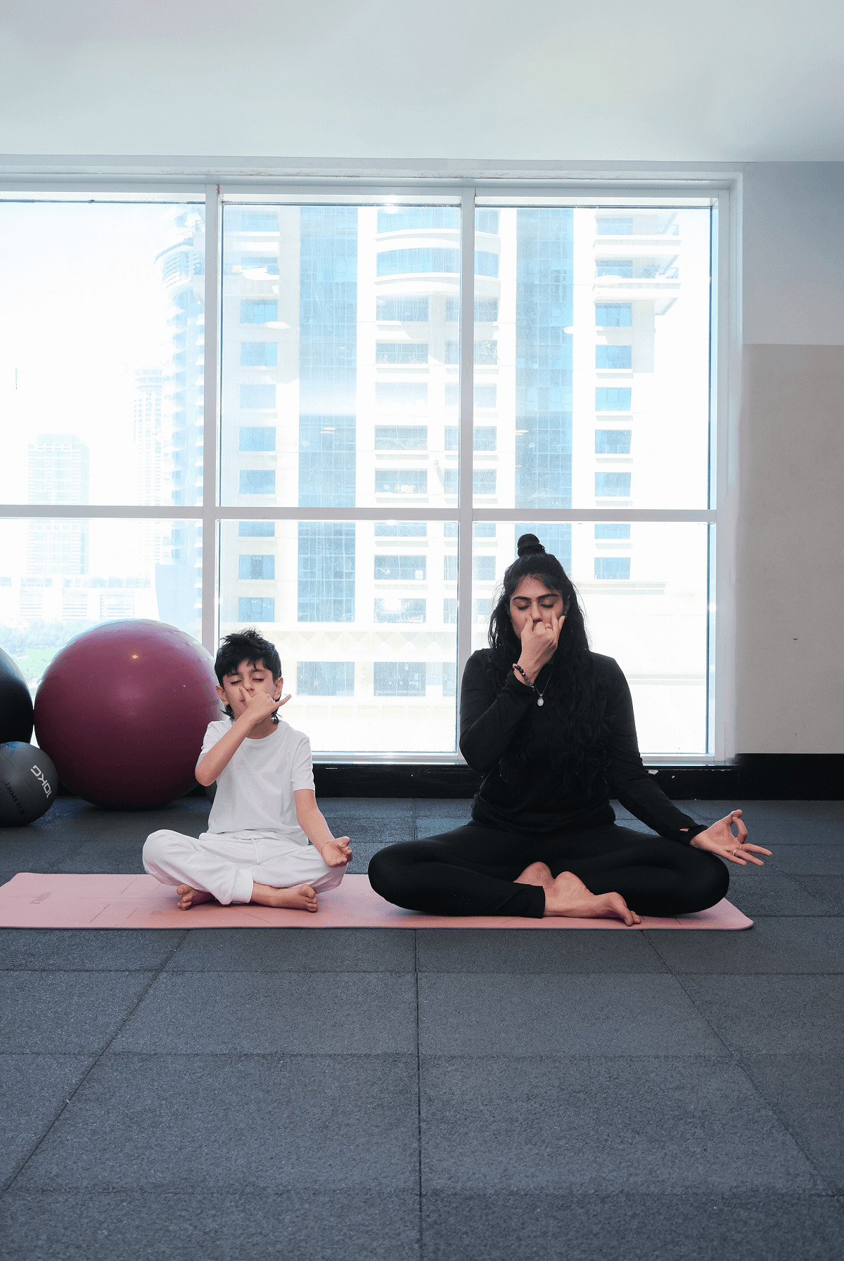 A Vyra teacher sits in meditation with a child on parallel mats